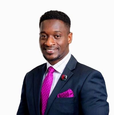 A confident man in a dark suit with a vibrant pink tie and pocket square.