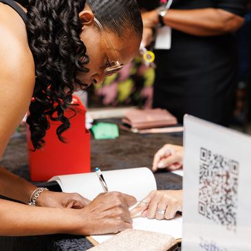 Woman signing a document at a table.