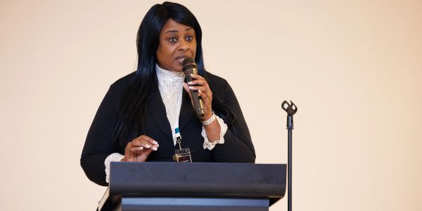 Woman speaking at a podium with a microphone.