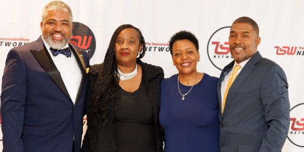 Four people posing at a formal event for The Successful Wives Network.