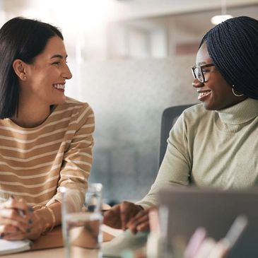 Two women smiling and talking in an office setting.
