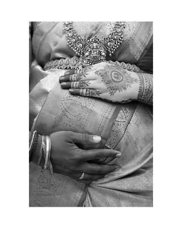Close-up of hands adorned with henna and jewelry on a traditional saree.