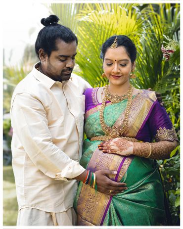 Pregnant woman in traditional attire with partner in a loving embrace.