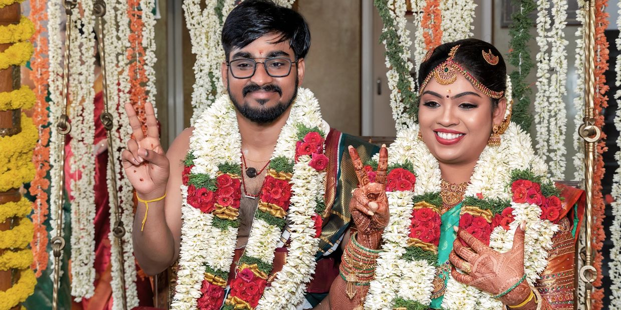 A joyful couple adorned with flower garlands celebrating their traditional wedding.