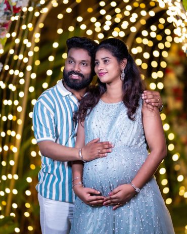 Happy couple celebrating pregnancy with warm lights in the background.