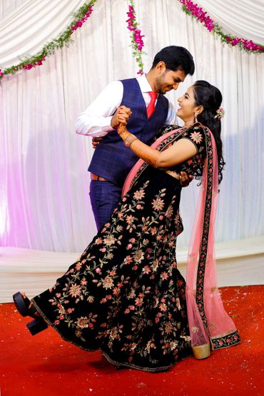 Couple dancing joyfully at a decorated event with floral garlands.