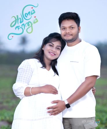 A happy couple embraces, celebrating pregnancy in a serene outdoor setting.