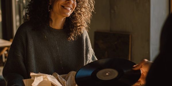 A woman happily receives a vinyl record from another person.