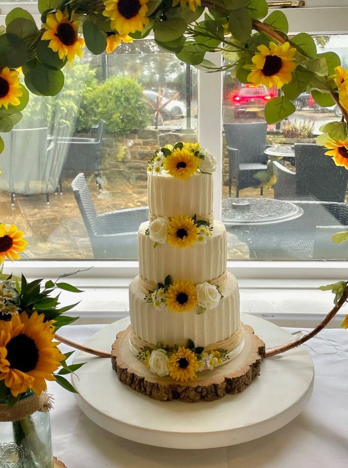 Rustic wedding cake with buttercream icing and sunflowers and white roses