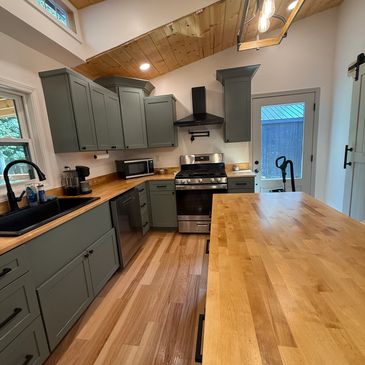 Modern kitchen with wooden countertops and green cabinets.