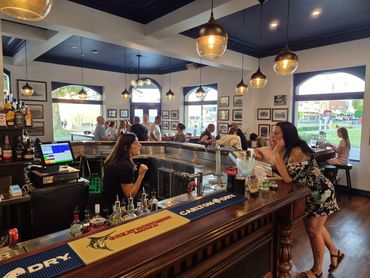 People socializing and ordering drinks at a cozy bar with warm lighting.