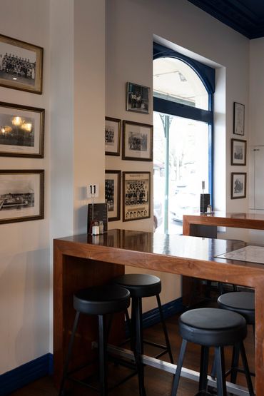Cozy corner in a cafe with wooden tables and black stools under a navy ceiling.