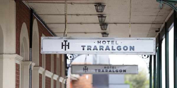 Sign for Hotel Traralgon hanging outside a brick building under a covered walkway.