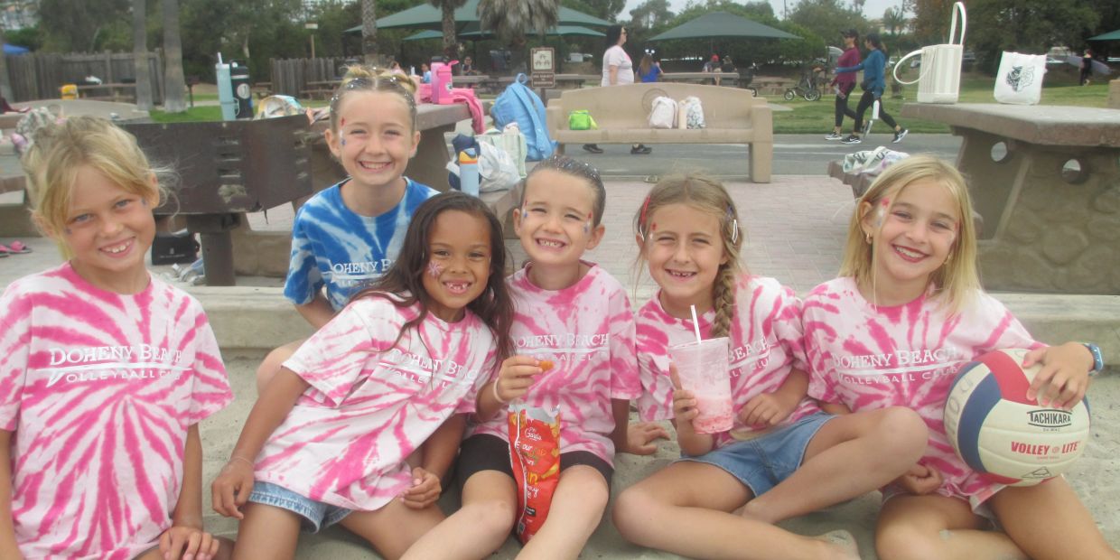 Group of six smiling kids in Doheny Beach Volleyball Camp shirts.