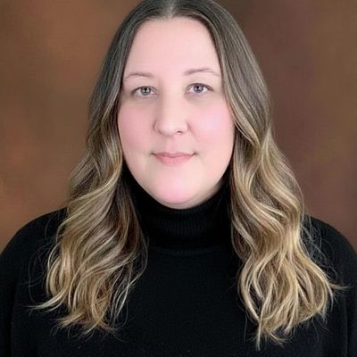 Portrait of a woman with wavy hair wearing a black turtleneck.