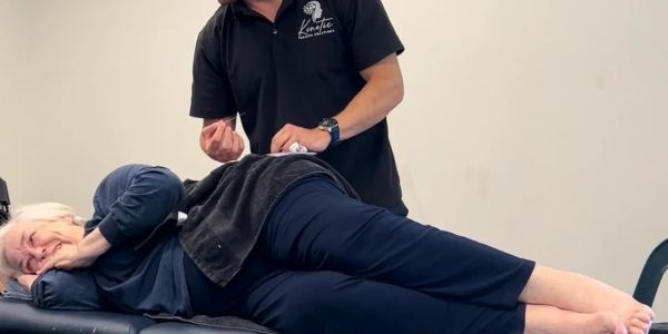 A person receiving acupuncture treatment while lying on their side.