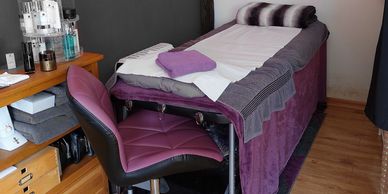 Beauty treatment room with purple chair and bed.