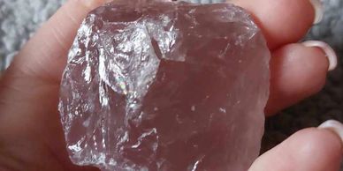 Large pink rough stone held in hand.