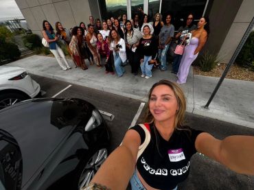 Woman taking selfie with a large group of smiling women.