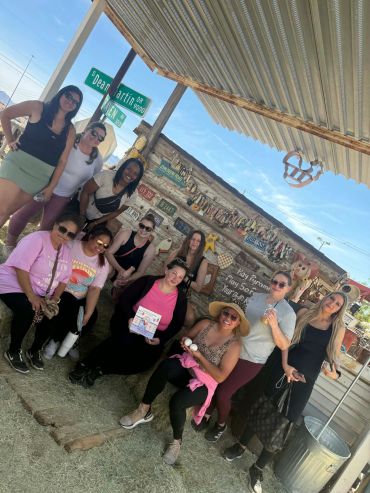Group of women posing under a shelter with street signs.