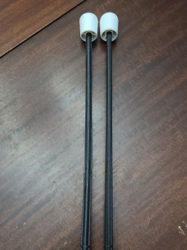 Two black plastic rods with white caps on a wooden surface.