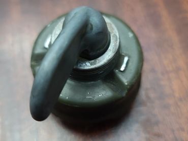 Close-up of a metal hook attached to a round base on a wooden surface.