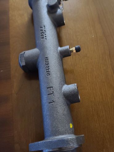 Metal pipe fitting with multiple threaded connectors on a wooden surface.