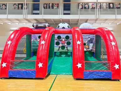 Inflatable sports game with football, soccer, and baseball themes indoors.