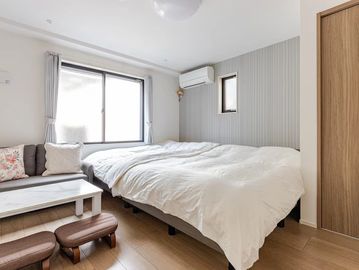 Bright, modern bedroom with twin beds, a small sofa, and wooden flooring.