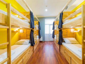 Bright hostel room with wooden bunk beds and yellow walls.
