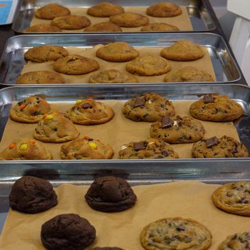 Trays of freshly baked assorted cookies cooling on parchment paper.