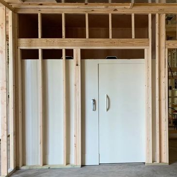 Unfinished wooden frame wall with a white door in construction site.