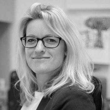 A smiling woman with blonde hair and glasses. Black and white photo.