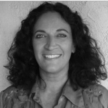 Caucasian woman with wavy black hair smiling towards the camera