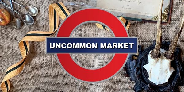 Uncommon Market Logo on a burlap backdrop surrounded by plates, books, art, and candles.