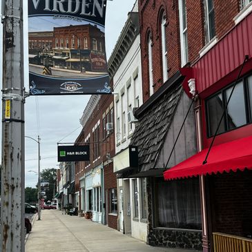 Street view of a small town with storefronts and a Virden banner.