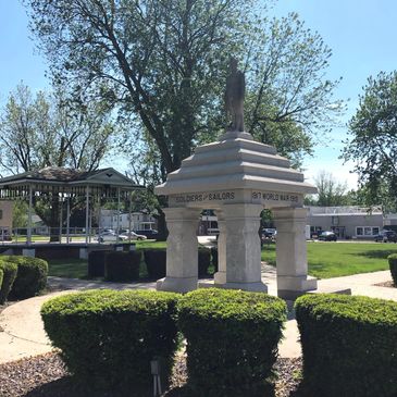 World War I memorial statue in a park with green bushes and trees.