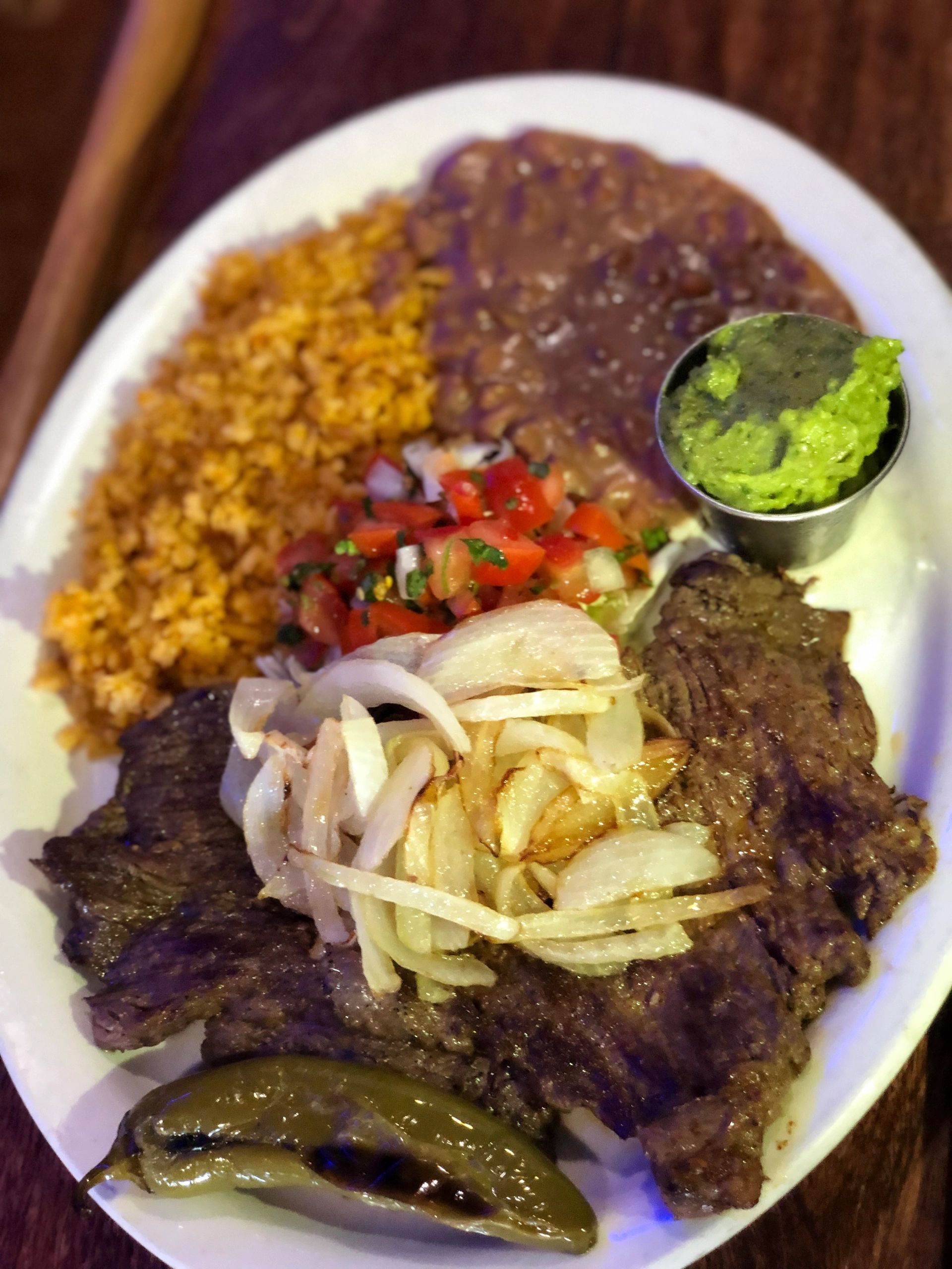 Carne Asada - Seasoned grilled flank steak, served with grilled jalapeno & onion, rice, beans and ho