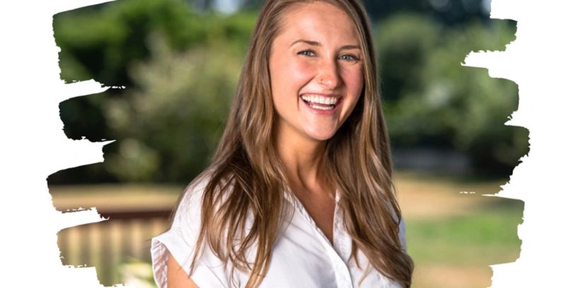 Smiling young woman outdoors with blurred greenery background.