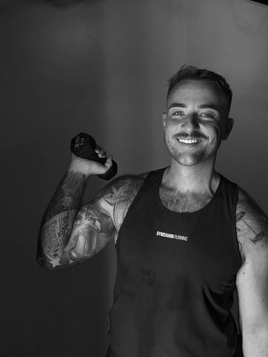 Smiling man lifting a dumbbell in a gym.