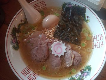 A bowl of ramen with sliced pork, egg, seaweed, and narutomaki.