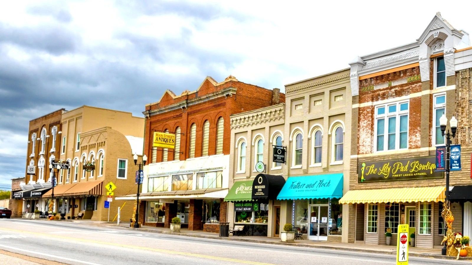 Historic downtown street with charming storefronts and cloudy sky.