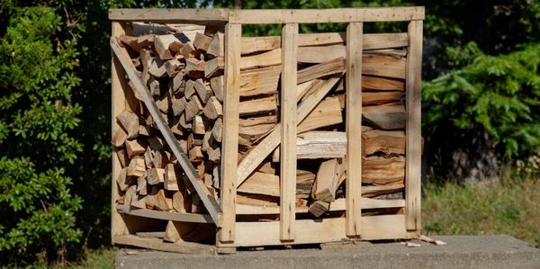 neatly stacked firewood on a pallet sitting on a slab of concrete