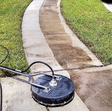 Pressure washing a curved concrete sidewalk showing clean and dirty areas.