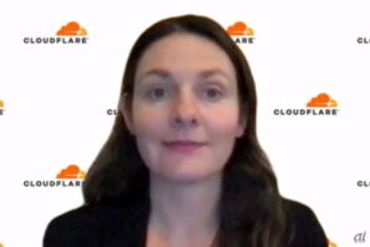 A woman in front of a Cloudflare logo backdrop.