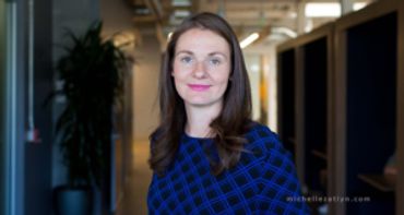 Professional woman with long brown hair in a blue checkered dress.
