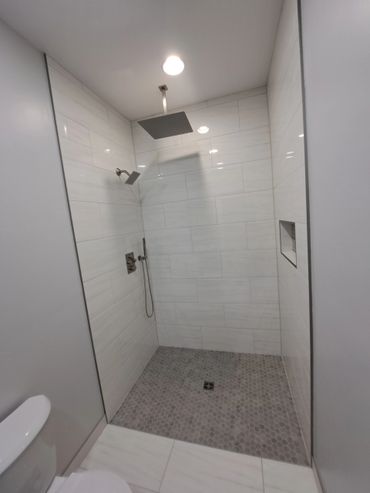 Modern walk-in shower with dual showerheads and gray hexagonal floor tiles.