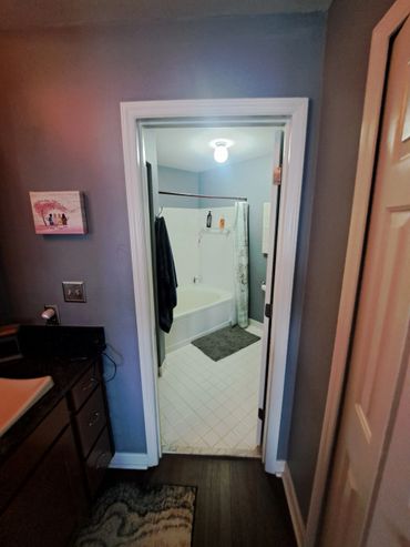 View of a bathroom with a bathtub, shower curtain, and bath mats.