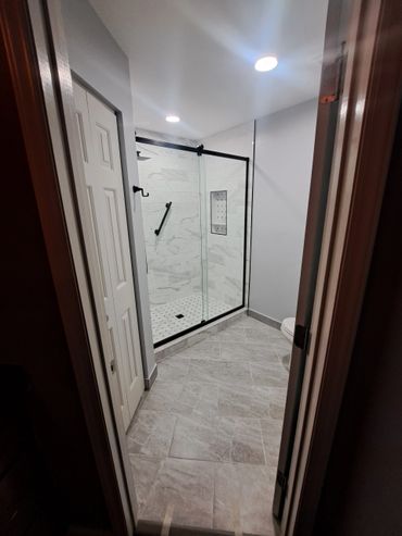 Modern bathroom with glass shower and tiled floor.