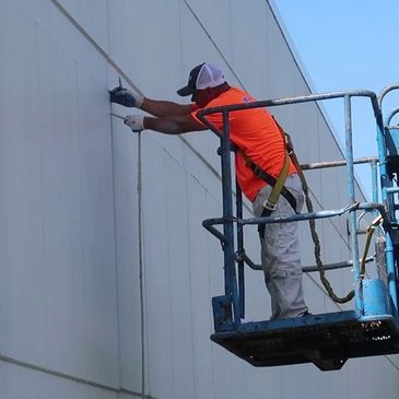 Worker in safety gear fixing wall from a lift platform.